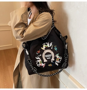 Dettaglio ricamo equestre su borsa tote in nylon nero con manici in corda intrecciata