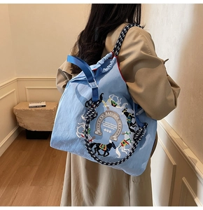 Dettaglio della borsa azzurra con ricamo a cavallo e tracolla intrecciata di design