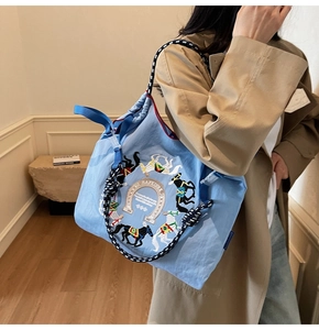 Dettaglio della borsa tote blu con ricamo a cavallo e manico in corda intrecciata