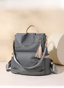 Detail of grey nylon backpack featuring khaki leather trim and side storage pocket