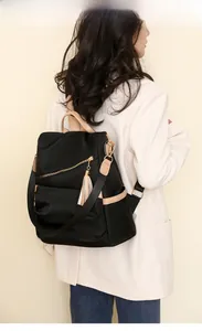 Rear view of a stylish black nylon backpack with tan leather straps and tassel detail