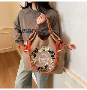 Dettaglio della borsa tote in oxford kaki con ricamo di cavalli e manici intrecciati arancio