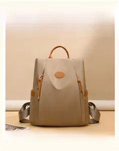 Detail of khaki waterproof nylon backpack with brown leather handle and logo patch