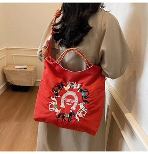 Dettaglio della borsa tote rossa con ricamo di cavallo indossata da una modella