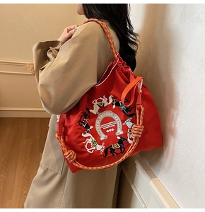 Dettaglio borsa tote in tela rossa con ricamo a cavallo, coulisse e manici intrecciati