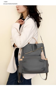 Detail of grey waterproof nylon backpack with gold zipper and stylish leather tassels