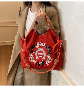 Dettaglio della borsa tote in tela rossa con ricamo di cavalli e manici intrecciati