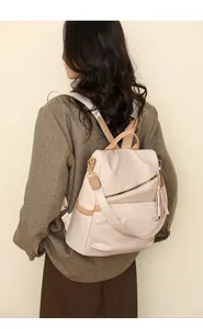 Detail of minimalist cream beige nylon backpack with tassel and brown PU leather accents