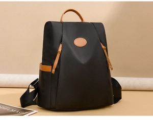 Close-up of waterproof black oxford backpack with brown leather handle and zipper detail