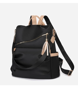 Detail view of a black nylon backpack with khaki leather trim and stylish tassel accents