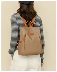 Detail of khaki anti-theft oxford backpack featuring orange leather handles and side pocket