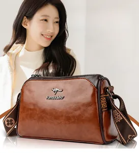 Detail view of vintage oil-waxed leather pillow bag with metal kangaroo logo and woven strap