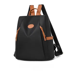 Waterproof black oxford fabric backpack with brown leather handles and accents in side view