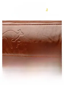 Detail of oil wax leather texture with brand kangaroo logo and precise stitching on bag