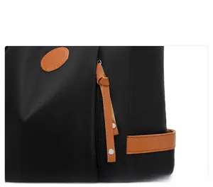 Macro shot of front zipper detail on black oxford backpack with brown leather accents