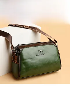 Detail of green leather handbag with wide bohemian strap and golden kangaroo logo