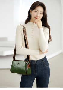 Close-up of dark green waxed leather pillow bag with floral strap and kangaroo logo