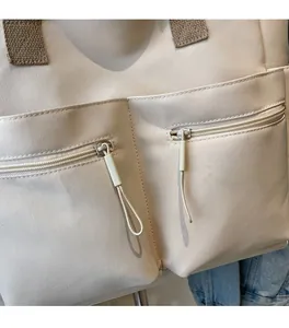 Detailed macro view of beige canvas tote bag with dual zipper pockets and cord pulls