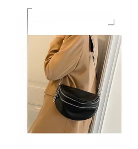 Detail of black lychee leather crescent chest bag with double silver zippers and webbing strap