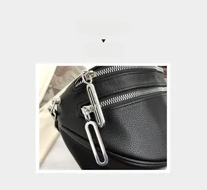 Detail of black textured leather crossbody bag with silver zippers and multi-layer design