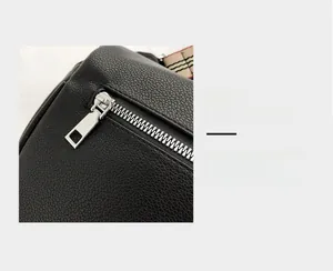 Macro detail of black litchi grain leather bag with silver zipper and striped strap
