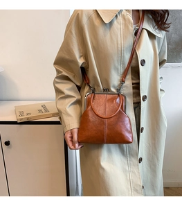 Detail of vintage brown kiss-lock crossbody bag featuring polished synthetic leather texture