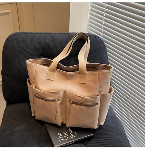 Detail of khaki canvas tote bag with functional pockets and sturdy straps on a chair