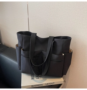 Detailed view of black canvas tote bag showing functional multi-pockets and wide straps