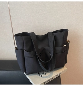 Detail of a black canvas tote bag with multiple pockets and heavy-duty ribbon handles