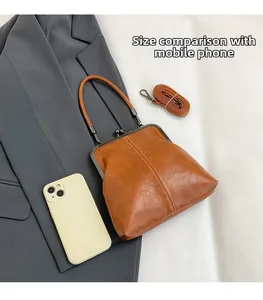 Brown vintage kiss-lock bag size comparison with a smartphone and detachable strap