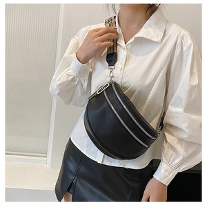 Detail of black pebbled leather crossbody bag featuring dual zippers and checked strap