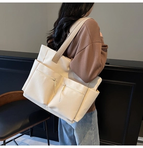 Detail view of large nylon tote bag with functional zippers and wide shoulder strap