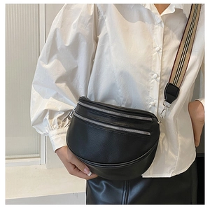 Detail of black crescent crossbody bag with grain texture and striped woven strap