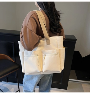 On-body view of large nylon tote bag with dual front pockets and wide fabric strap