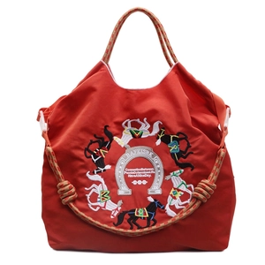 Borsa tote rossa con ricamo di cavalli e tracolle intrecciate su sfondo bianco pulito