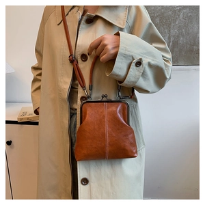 Detail view of brown shell-shaped crossbody bag with metal clasp and visible stitching