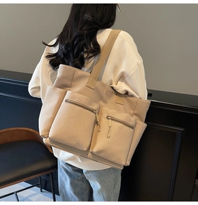 Detail of light beige canvas tote bag showing side pockets and wide shoulder straps