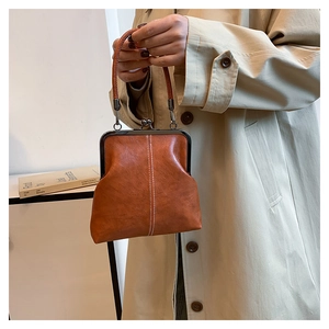 Detailed shot of brown vintage leather handbag with white stitching and metal clasp