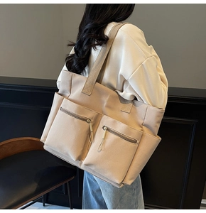 Detail view of large beige canvas tote bag showing two spacious front zipper pockets