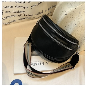 Detail of black pebbled leather crescent bag with dual silver zippers and striped strap