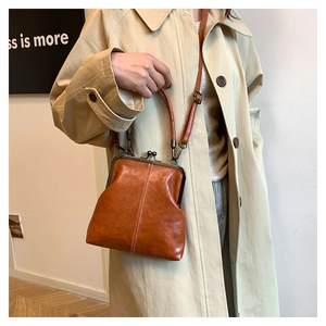 Close-up of retro brown PU leather shell bag featuring vintage metal clasp and top handle