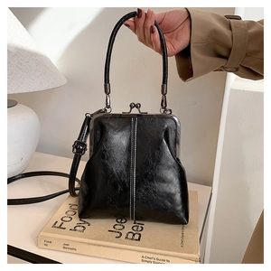 Close-up of a retro black high-gloss oil wax leather handbag with metal kiss-lock closure