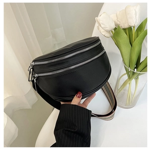 Detail view of the black pebbled leather crossbody bag with dual silver zippers and stripe strap