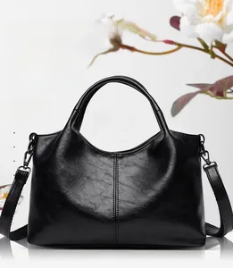 Detail of soft black leather tote with fixed handles and detachable crossbody strap