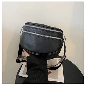 Close-up of black pebble leather crossbody bag with striped strap and double zippers