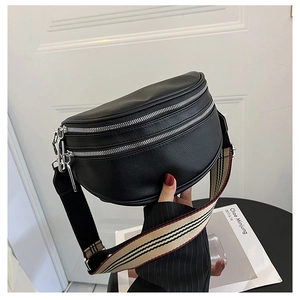 Detail of black pebbled leather waist bag featuring dual zippers and striped canvas strap