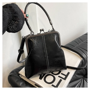 Detail of vintage black kiss-lock handbag with glossy texture and contrast stitching