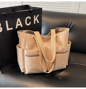 Detailed view of beige canvas tote bag with functional front zippers and side pockets