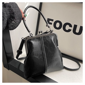 Detail of black vintage kiss-lock handbag with oil wax texture and white stitching details