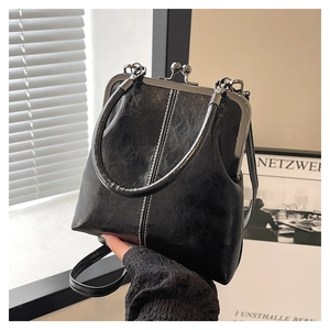 Macro shot of retro black oil wax leather handbag with white stitching and metal frame